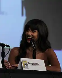 Jamil smiles with a black microphone in front of her