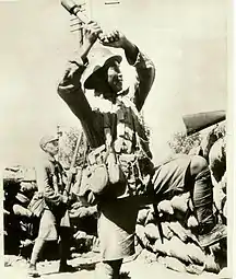 Chinese soldier wearing a German helmet holding an M24-style grenade.