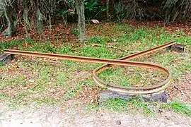 Rusted railroad rail bent in a circle, known as a Sherman's necktie