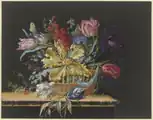 Blumenkorb mit Tulpen, Levkojen, Rittersporn und anderen Blumen auf einem Tisch