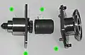 A partially-disassembled CBM Powered Bolt, showing both ends of the shaft (1), the lower housing (2) that nestles into the ACBM ring, the drive sleeve (3) and its spline interface with the shaft, and the upper housing (4). The upper housing and drive sleeve can be removed without demating the vestibule to install a spline lock under an IVA seal “butter dish”. The spline lock prevents the bolt from backing out.