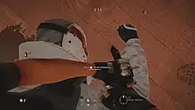 A masked man is pinned down by an interrogator with a knife.