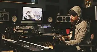 Charlie Handsome writes a song in the recording studio while playing guitar in a gray hoodie
