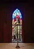 Lady Chapel stained glass window, commissioned in 2004. A wahine (woman) draped in a korowai with pounamu cross necklace holding Te Paipera Tapu (the Māori Bible) framed by Luke 1:46-47. Below her are crests of Te Pīhopatanga o Te Tai Tokerau. Above her are doves.