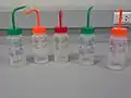 The back of wash bottles with labels for indicating types of substances inside.
