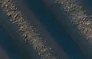 Close-up View of dunes in previous image, as seen by HiRISE. Note how sand barely covers some boulders.