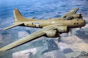 Large green four-engine propeller-driven aircraft in flight.