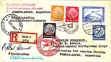 The reverse of a postcard. The consignee's address is in Buenos Aires, Argentina. It bears (on the right, above the address) 25 ℛℳ worth of postage stamps and a special Deutsche Luftpost stamp for 2 ℛℳ. The stamps are cancelled by a postmark: "Berlin, 26.5.34", and a red cachet saying: "Deutsche Luftpost: Europa-Sudamerika" with a motif of a zeppelin and a Dornier Wal. On the left is the receiving postmark: "Buenos Aires, Argentina 31 May 1934"