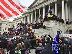 Crowds of supporters are dense on the steps of the U.S. Capitol building, waving Trump flags.