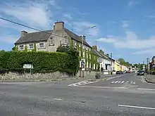The is an image of Collon House located just off Drogheda street at the crossroads in Collon, Co.Louth on a sunny day. Green hedges surround the house making it more private from the streets.