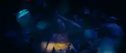 Dua Lipa dancing in a crowded nightclub.