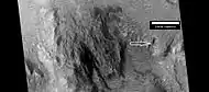 Close view of central portion of Auki Crater, as seen by HiRISE  Arrow indicates ridges.  Sand dunes are present near the top of the image.
