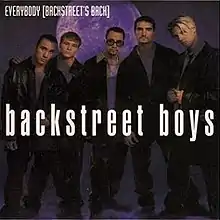 The band is standing in front of a purple background.
