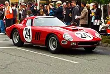 Bright red racing car, number 24, next to a crowd