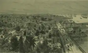 Sketch of Georgetown, Demerera, British Guiana showing the town on the left, people and horses walking on the main waterfront street, and the harbour on the right, filled with ships