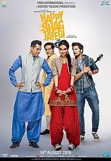 Four young, Indian people—three men and one woman—standing. The man (left) and woman wear colourful, traditional Indian dress. In the background one man (left) wears a long, yellow overcoat and the other (right) wears Western casual clothes (shirt and jeans).