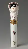 "Toy" needlecase with the head of Columbina, c. 1760, height: .mw-parser-output .frac{white-space:nowrap}.mw-parser-output .frac .num,.mw-parser-output .frac .den{font-size:80%;line-height:0;vertical-align:super}.mw-parser-output .frac .den{vertical-align:sub}.mw-parser-output .sr-only{border:0;clip:rect(0,0,0,0);clip-path:polygon(0px 0px,0px 0px,0px 0px);height:1px;margin:-1px;overflow:hidden;padding:0;position:absolute;width:1px}4+7⁄8 inches (12&nbsp;cm). Inscribed on enamel band on mount: NE SOYEZ POINT CRUELE ("Don't be so cruel")