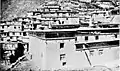 A corner of the three-storey monastic print house (Derge Parkhang) in 1918, with parts of the larger monastery visible in the background above.