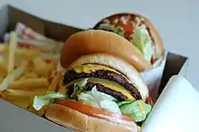 An In-N-Out "Double-Double" cheeseburger with fries in a box for consumption in a car