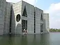 Image 36Jatiyo Sangsad Bhaban is the National Assembly Building of Bangladesh, located in the capital Dhaka. It was created by architect Louis I. Kahn and is one of the largest legislative complexes in the world. It houses all parliamentary activities of Bangladesh. This photo offers a close view of a section of the parliament building.Photo Credit: justinstravels