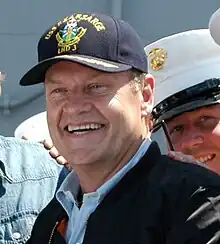 A man wearing a cap smiles broadly.