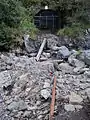 The mine viewed from the foot of the mill. A half-buried piece of rail is still extant.