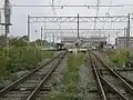 A view of the platforms and tracks. The train is standing on track 3 which is a siding. To the right, some sidings can be seen between the island platform and the station building.