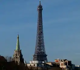 A close-up view of the spire from the Invalides bridge, with the Eiffel Tower in the background