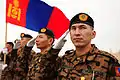 Mongolian soldiers salute while the Mongolian flag waves at the Transit Center at Manas, where they stayed for several days before moving forward to Afghanistan to support Operation Enduring Freedom.