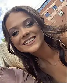 Woman with dark brown hair smiling.