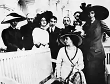 People in elaborate clothing standing around a bench