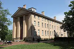 beige, brick building with many windows on the right side of the building.