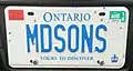 Personalized plate (front) attached to a pickup truck. Note that as a pickup truck it should otherwise bear a black on white commercial plate, but the personalized plate is blue on white. Validation and "personal use" tags are affixed to the front plate, as in the case of other pickups.