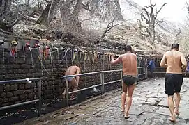 Pilgrim passing under the freezing water from 108 holy spouts with friends filming
