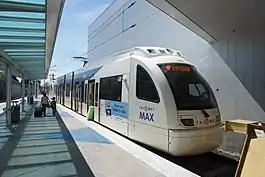 A MAX train stopped with its doors open and passengers boarding it at Portland International Airport station