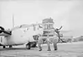 Royal Air Force personnel pass in front of a B-24 Liberator aircraft at Kallang airport, Singapore, in 1945–46.