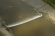 A tidal bore wave moves along the River Ribble between the entrance to the river Douglas and Preston.