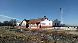 A building which is 195 feet (59&nbsp;m) long and 26 feet (7.9&nbsp;m) wide. The building architecture is eclectic, exhibiting both Spanish and Italian influences. The lower section of the exterior wall is brick, while there is covered with stucco. The stucco is painted white, decorated with tan painted trim. The center section has a gabled roof, with semicircular walls extending above the roof line on each end. The large window in the center is arched. Other windows have an arch design embedded in the stucco.