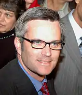 Photograph of a man wearing a suit and glasses