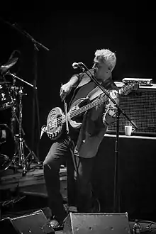 Black and white picture of South Asian man playing a stringed instrument onstage