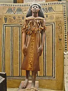 Small wooden statue of a striding man wearing a kilt