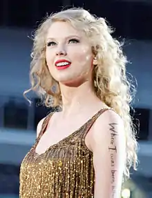 A woman performing on a microphone, wearing a golden yellow dress