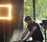 A color photograph of The Haxan Cloak, who is performing live at a 2014 music festival.