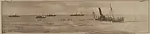 B&W image of a half-sunken ship stranded just off shore