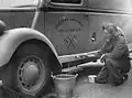 Mrs Jack Miller of the American Ambulance, Great Britain, paints a white line around the bottom of her ambulance, in order to make it more visible in the blackout.