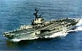 Medium-size aircraft carrier with numerous aircraft on its flight deck.