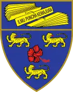 A shield displaying a coat of arms; on a dark blue background, an open book displays the words "Dominus illuminatio mea", with two gold crowns above and one below