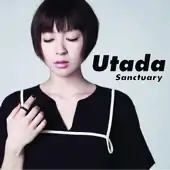 A portrait of Hikaru Utada standing in front of a light-blue screen. They are wearing black clothing and looking at their left hand.