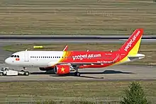 An aircraft of VietJet Air with the National flag painted below the windshield. The yellow-star-on-the-red-background symbolism of the Vietnamese flag is also used to decorate the engine.