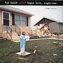 A plastic figurine of Jesus Christ on a lawn next to a home that has been demolished